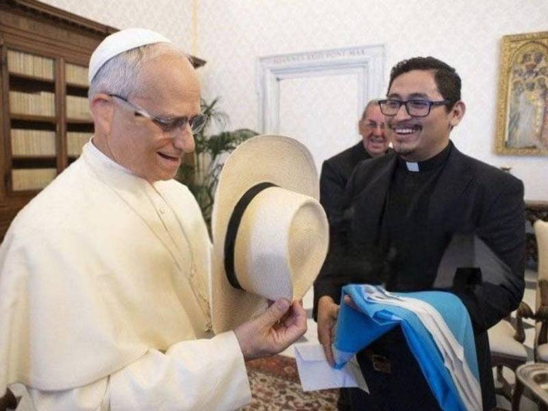 El Papa León XIV, recientemente elegido como el 267º pontífice de la Iglesia Católica, fue homenajeado por miembros de la iglesia hondureña, quienes le entregaron dos recuerdos de la tierra catracha: la bandera de Honduras y un sombrero artesanal hecho en Santa Bárbara. Aquí las imágenes.